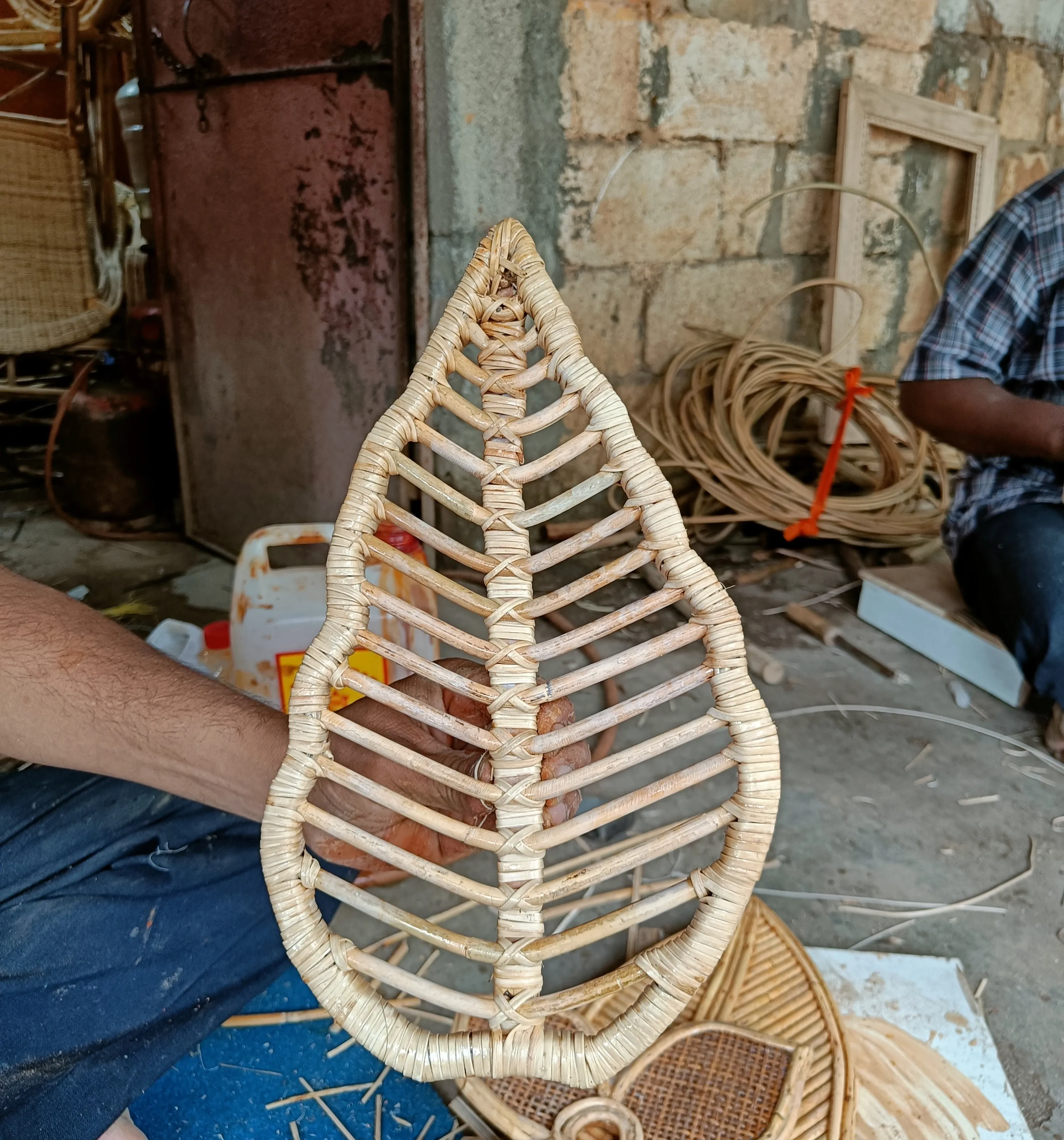 Artisan holding a hand-woven cane leaf component, Malappuram